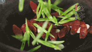 先后下香腸片、四季豆絲均勻翻炒，加適量清水燜煮一下。