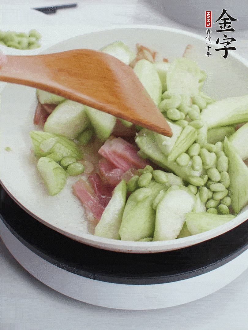 依次下絲瓜、青豆翻炒，炒至絲瓜打蔫縮小。
