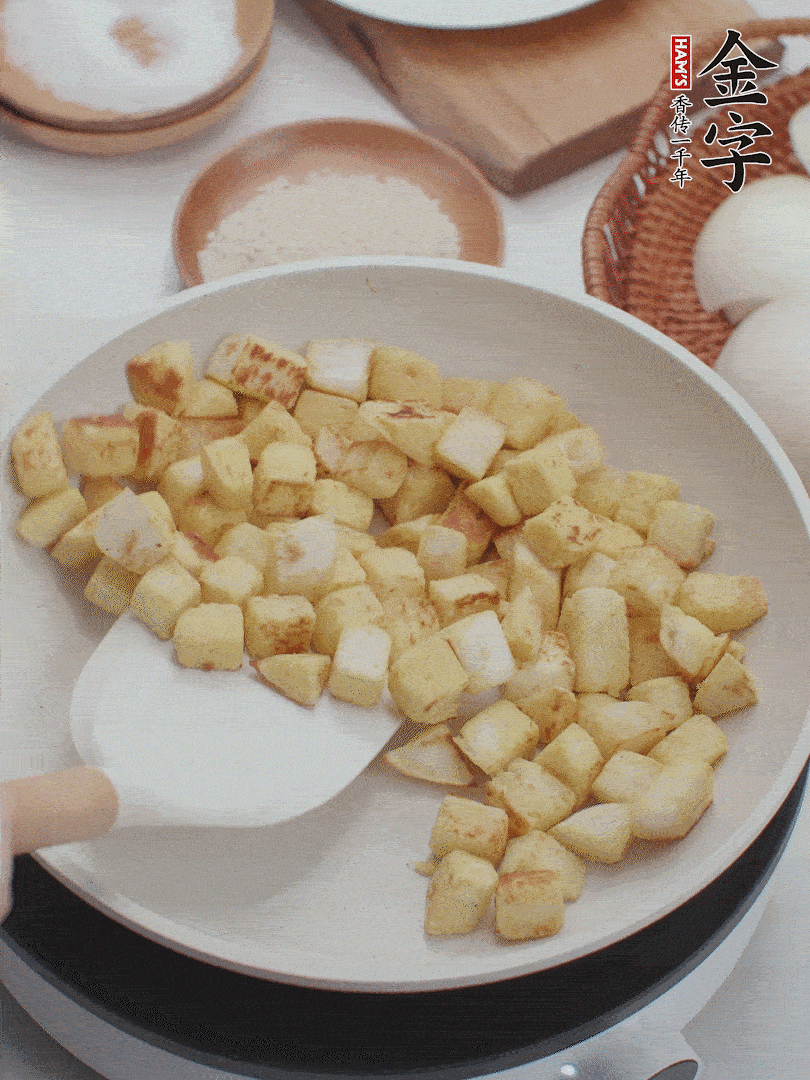 起鍋熱油，倒入饅頭丁，小火煎至蛋液凝固定型再翻面，饅頭丁部煎至金黃時(shí)盛起待用。