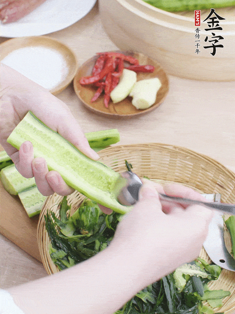 黃瓜削皮，對半切開，勺子挖去內(nèi)瓤，斜刀切片。青蒜斜刀切段。