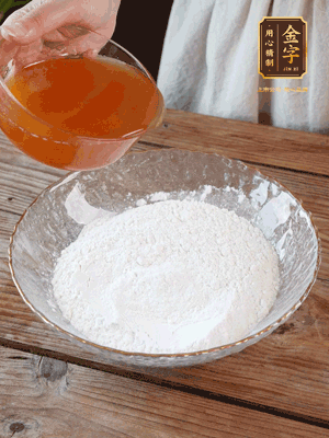 轉(zhuǎn)化糖漿、枧水、花生油攪拌均勻，加入面粉混合，醒發(fā)2小時(shí)。捏成23g一個(gè)的小球