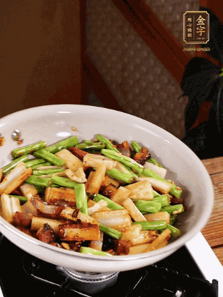 油熱下蒜末、干辣椒、醬肉煸炒出香味，依次下藕條、豆角翻炒均勻